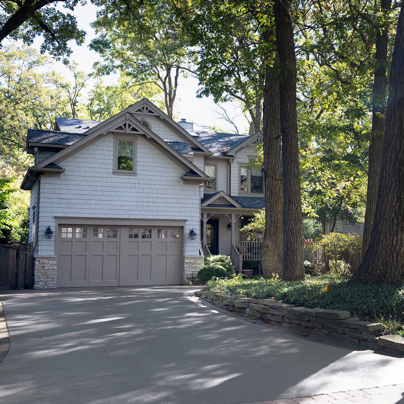 A house with a driveway and garage with trees surrounding it