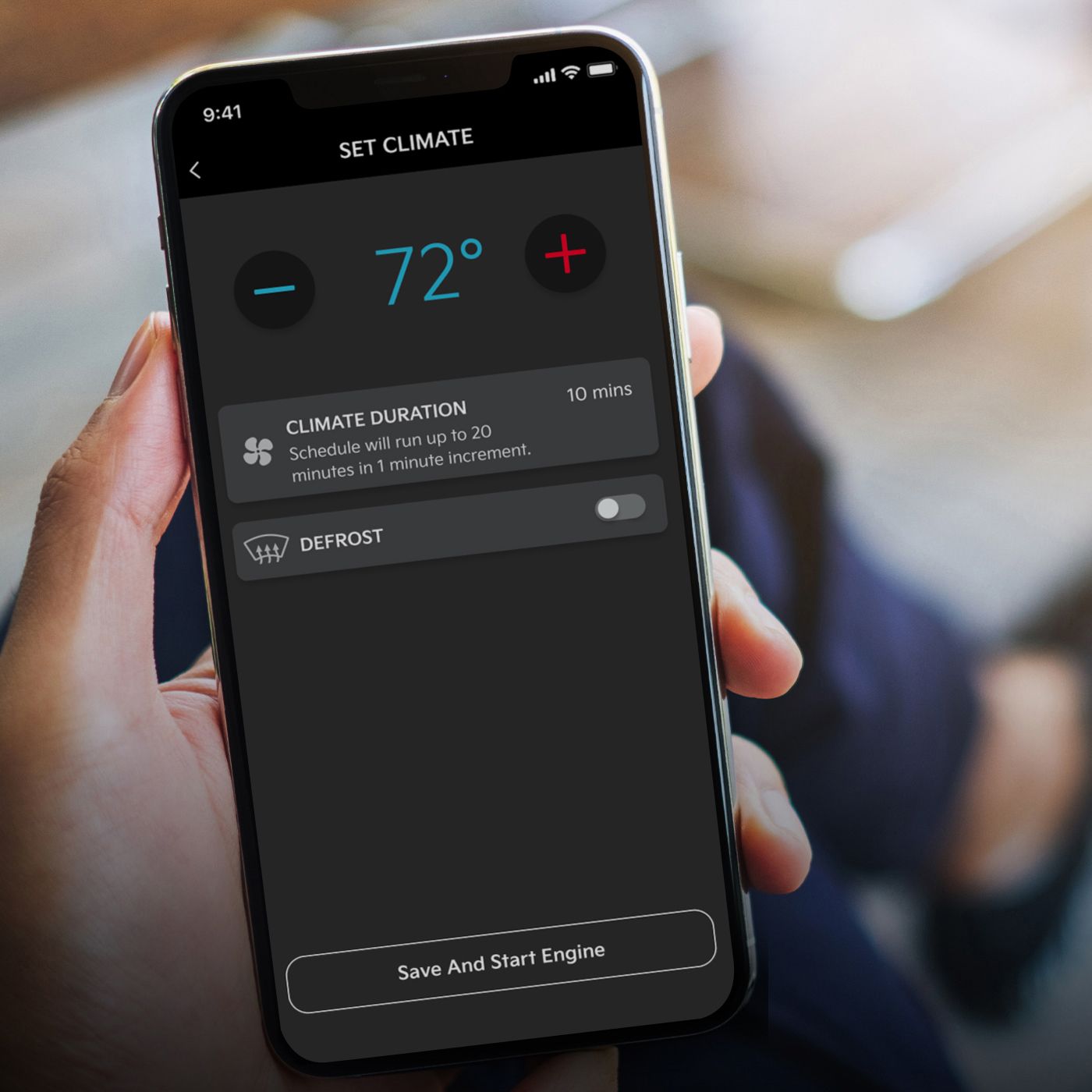 A hand holding a phone with a screen that displays the car temperature settings
