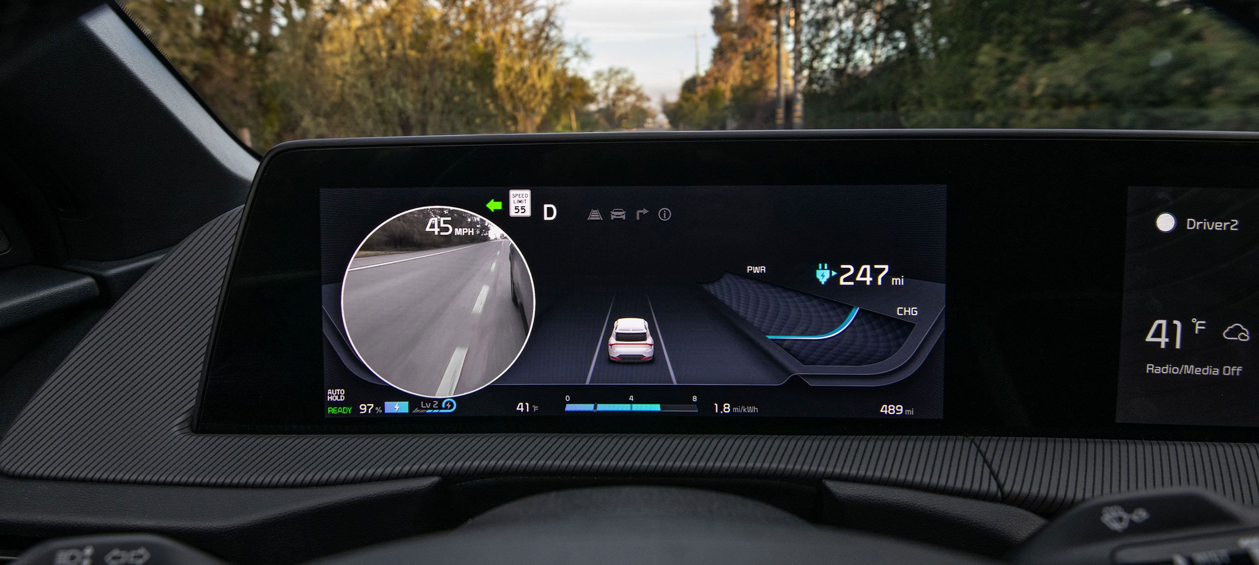 Close-up image of the digital blind-spot view monitor inside the 2026 Kia EV6, showing a live feed of a vehicle's blind spot when a turn signal is activated, as well as other important driving information.