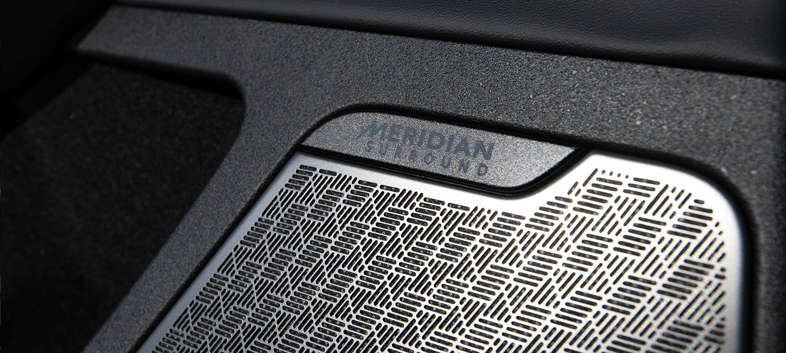 Close-up shot of a speaker with a distinct linear cross-hatch pattern and the words Meridian Surround, inside the 2026 Kia EV6.
