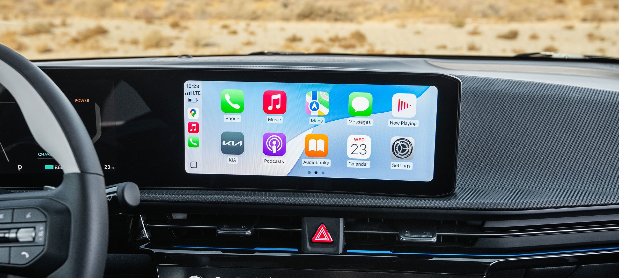 Close-up shot of the center console inside the 2026 Kia EV6, displaying wireless connectivity options compatible with Apple CarPlay and Android Auto, showing apps like Phone, Music, Maps, Messages, Now Playing, the KIA app, and more.