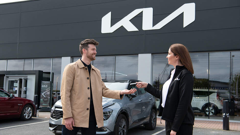 Models shaking hands in a Kia dealership
