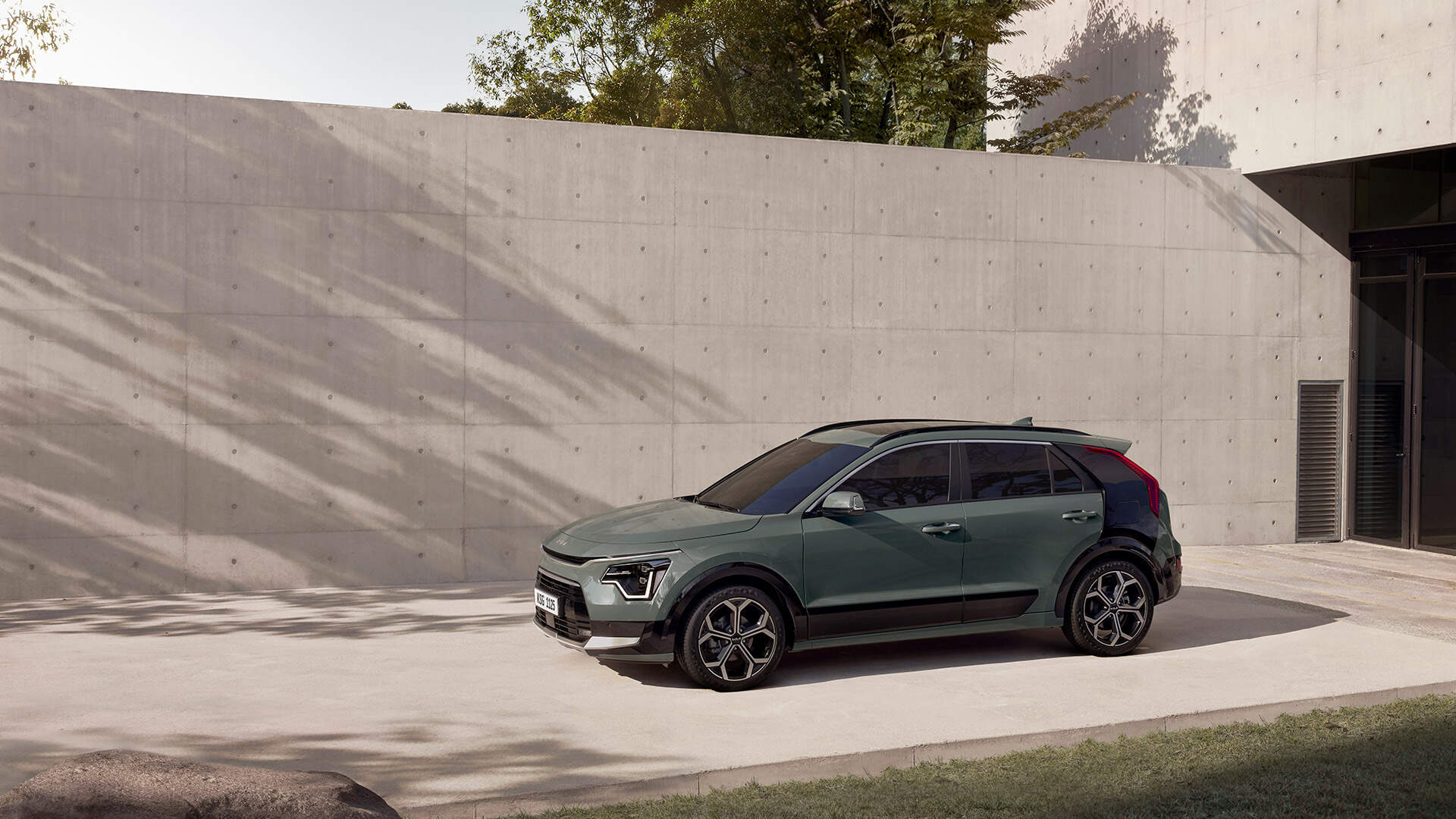 A Kia Niro is parked in front of a concrete wall