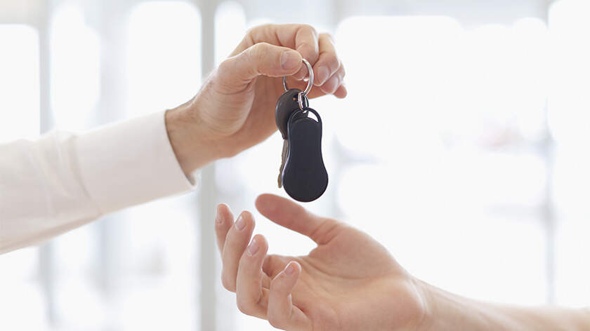 A man handing car key to another person