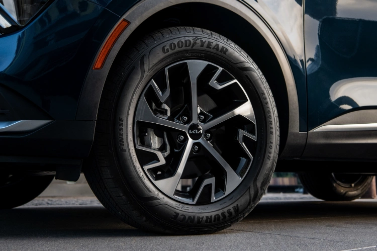 Vista ampliada del neumático delantero con tracción en las cuatro ruedas (AWD) activa del Kia Sportage Hybrid 2024 en azul