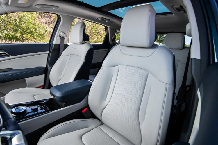 2024 Kia Sportage Hybrid interior, three-quarter view of the driver and passenger seats featuring light grey leather seats