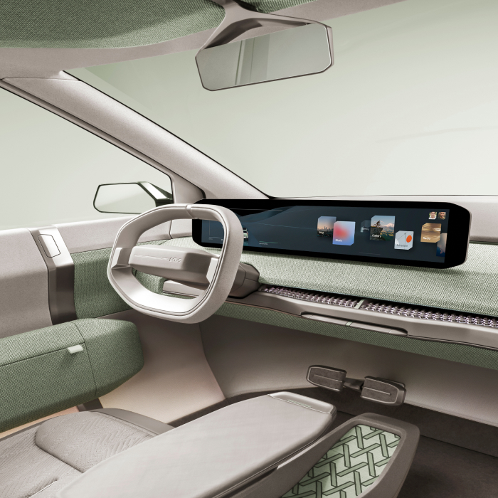 Interior del prototipo Kia EV3, vista del asiento del conductor, con pantalla digital panorámica y detalles interiores en verde claro.