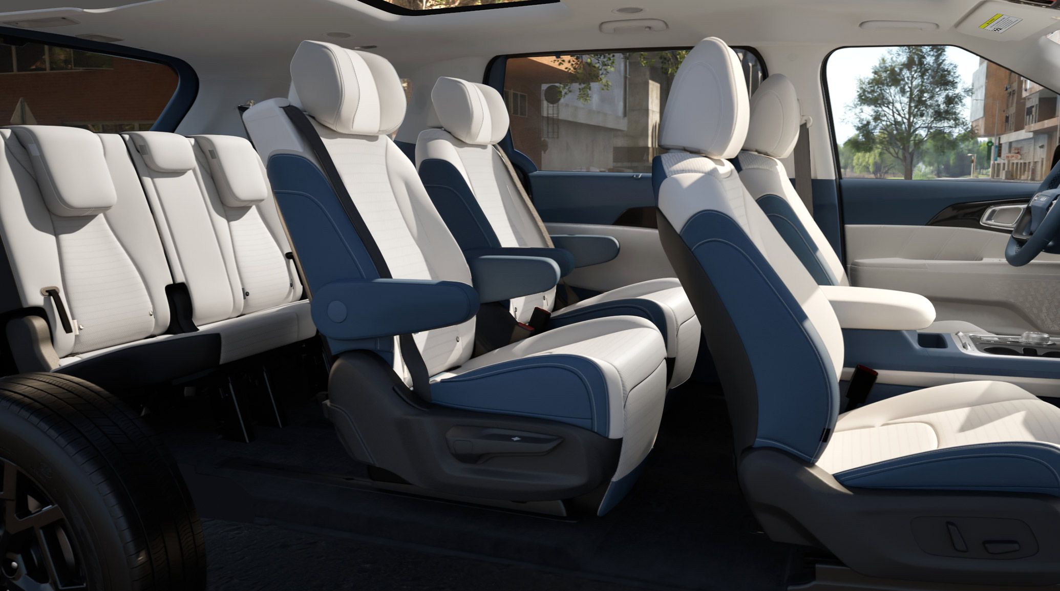 Three-row interior of the 2027 Kia Carnival Hybrid SX Prestige featuring navy and gray leather‑trimmed seats, shown from a wide cabin angle that emphasizes spacious legroom, premium stitching, and the full layout of all seating rows.