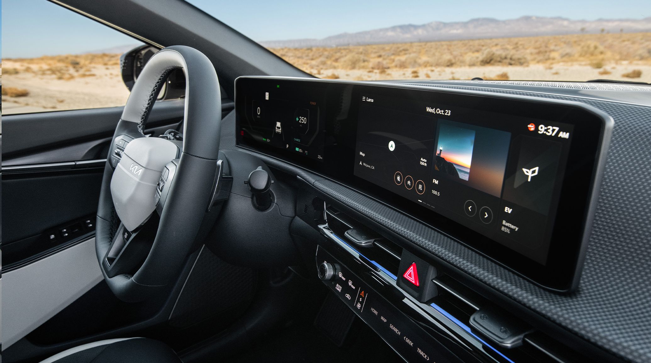Interior view of the 2026 Kia EV6 GT-Line All Wheel Drive electric CUV focusing on the 24 inches of combined panoramic dashboard displays. The photo also includes the steering wheel and the wide open desert outside the windows of the vehicle.