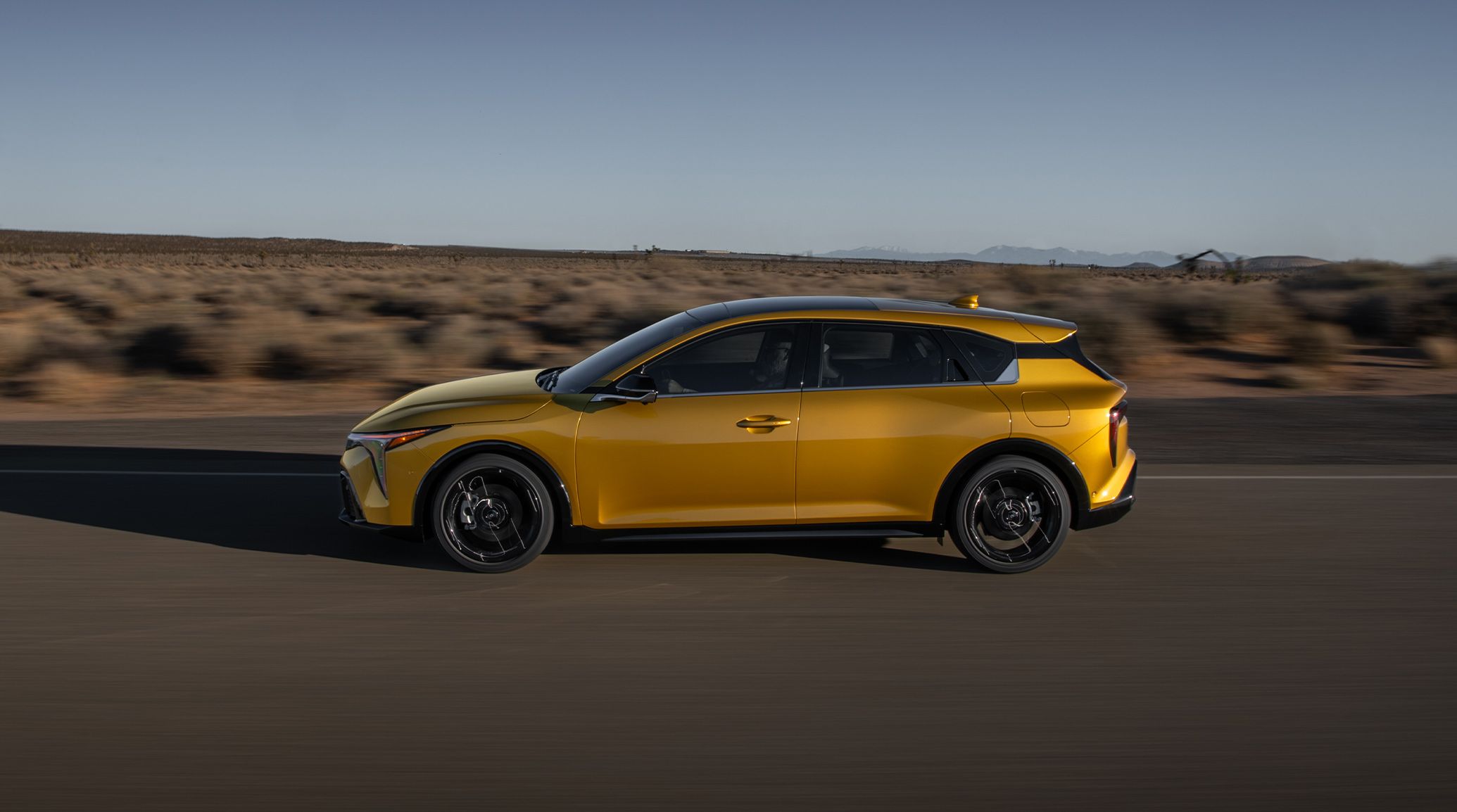 Dynamic shot of the 2026 K4 Hatchback GT-Line Turbo, emphasizing the LED Turn Signals in the side view mirror as it drives through the desert.
