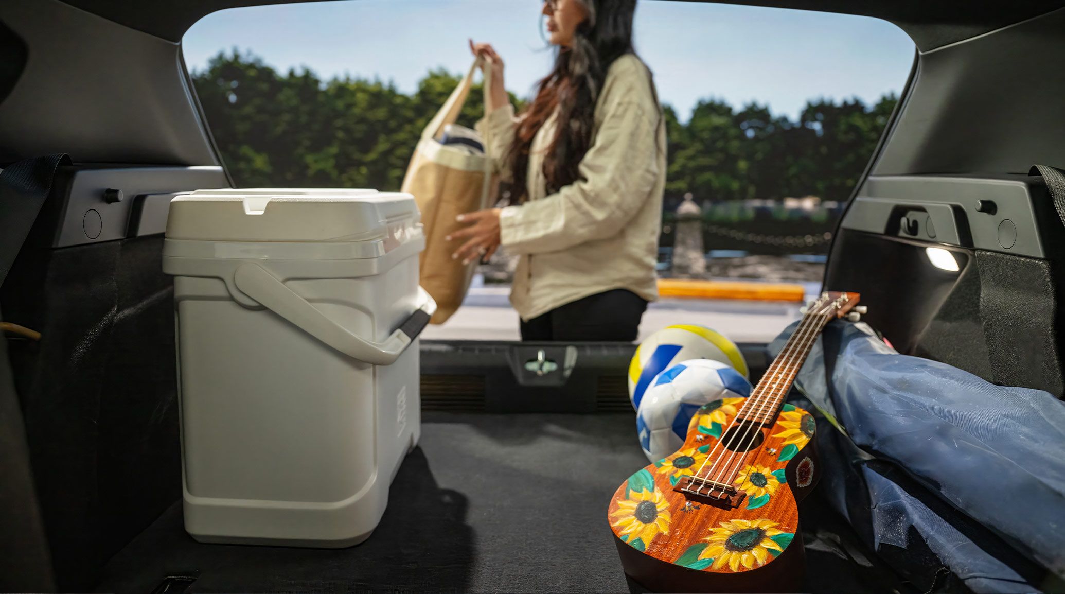 A still shot taken from the inside of a 2026 K4 Hatchback GT-Line Turbo, where a woman is unloading 59.3 cubic feet of cargo space within the K4 Hatchbach with the rear seats folded.