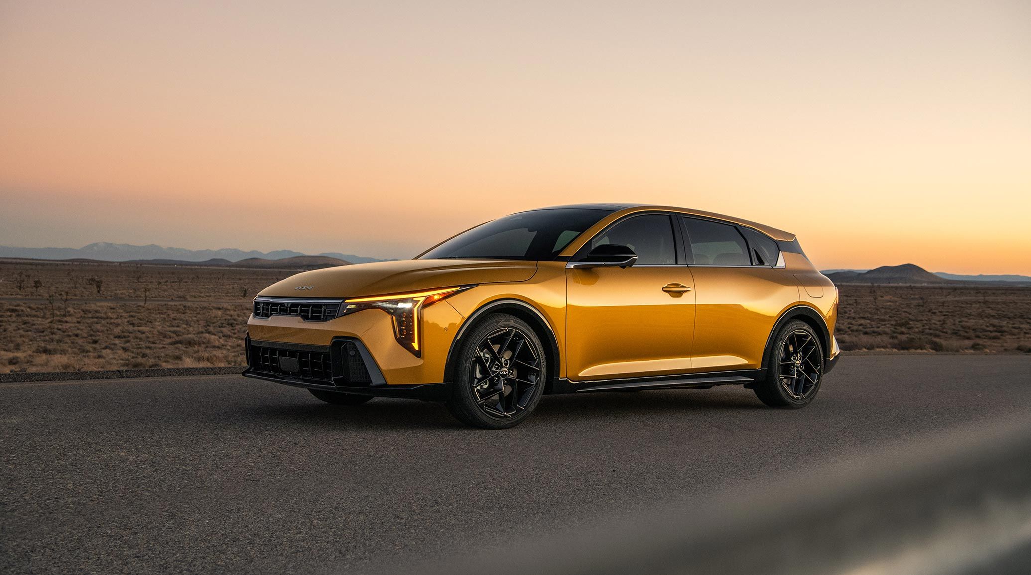 A non-dynamic side-shot of the 2026 K4 Hatchback GT-Line Turbo in the desert landscape, accentuating the Gloss Black Side View Mirrors and the Satin Chrome Window Trims for the vehicle.