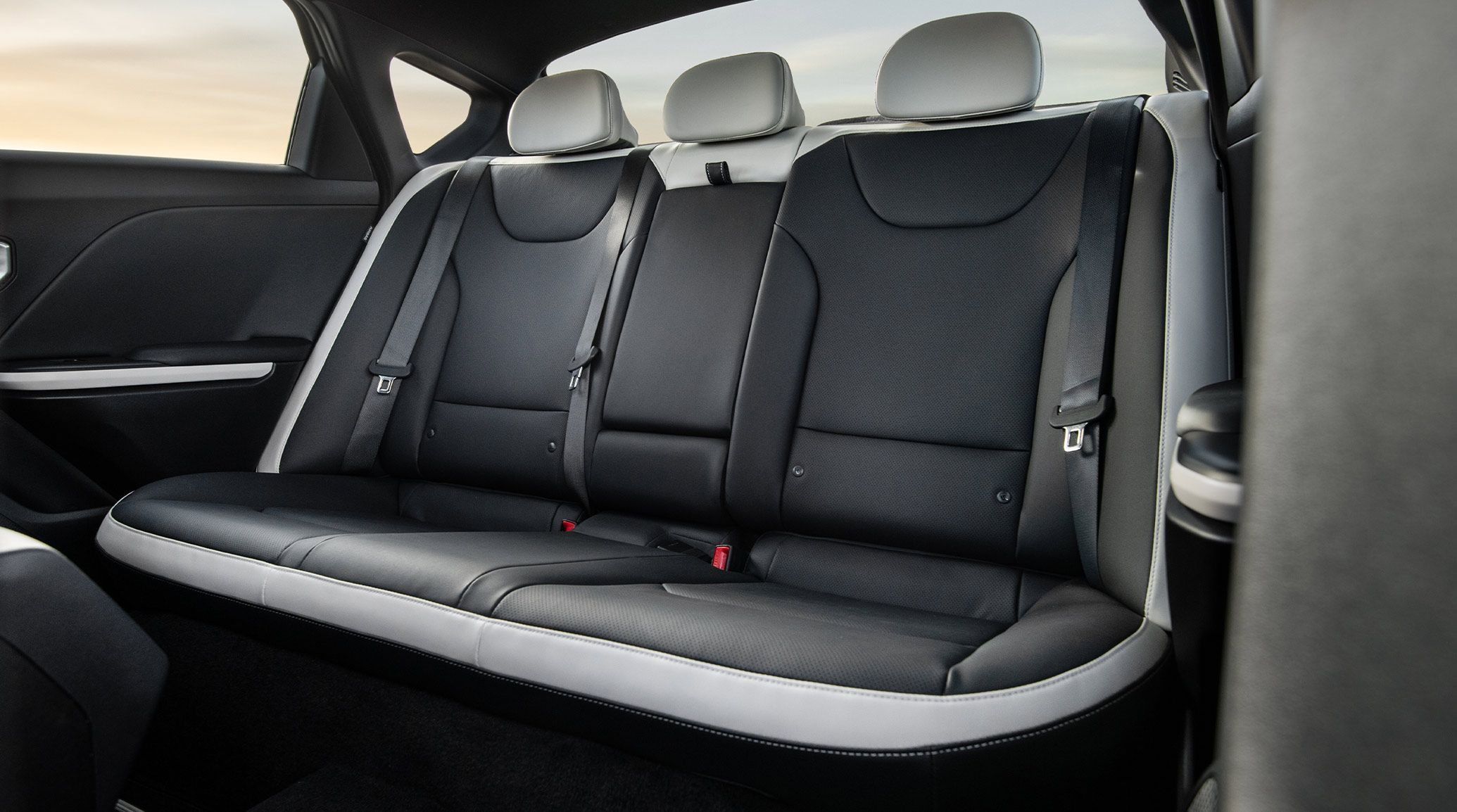 Interior view of the 2026 Kia K4 sedan's back row of passenger seating and space, highlighting the black and white SynTex seat trim and folding armrests with cupholders