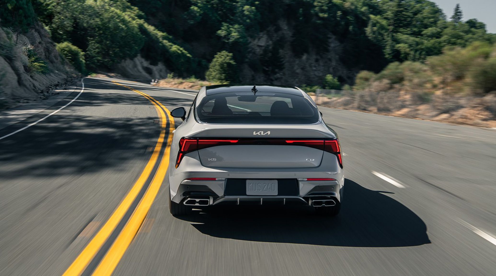 rear view of Kia K5 KS driving on mountain road.