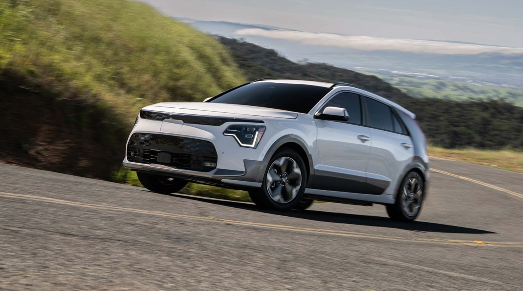 2026 Kia Niro EV driving upwards on a steep hill, front three-quarter view