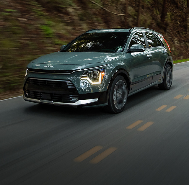 2023 Kia Niro Hybrid Driving Fast On A Road In The Forest Three-Quarter View