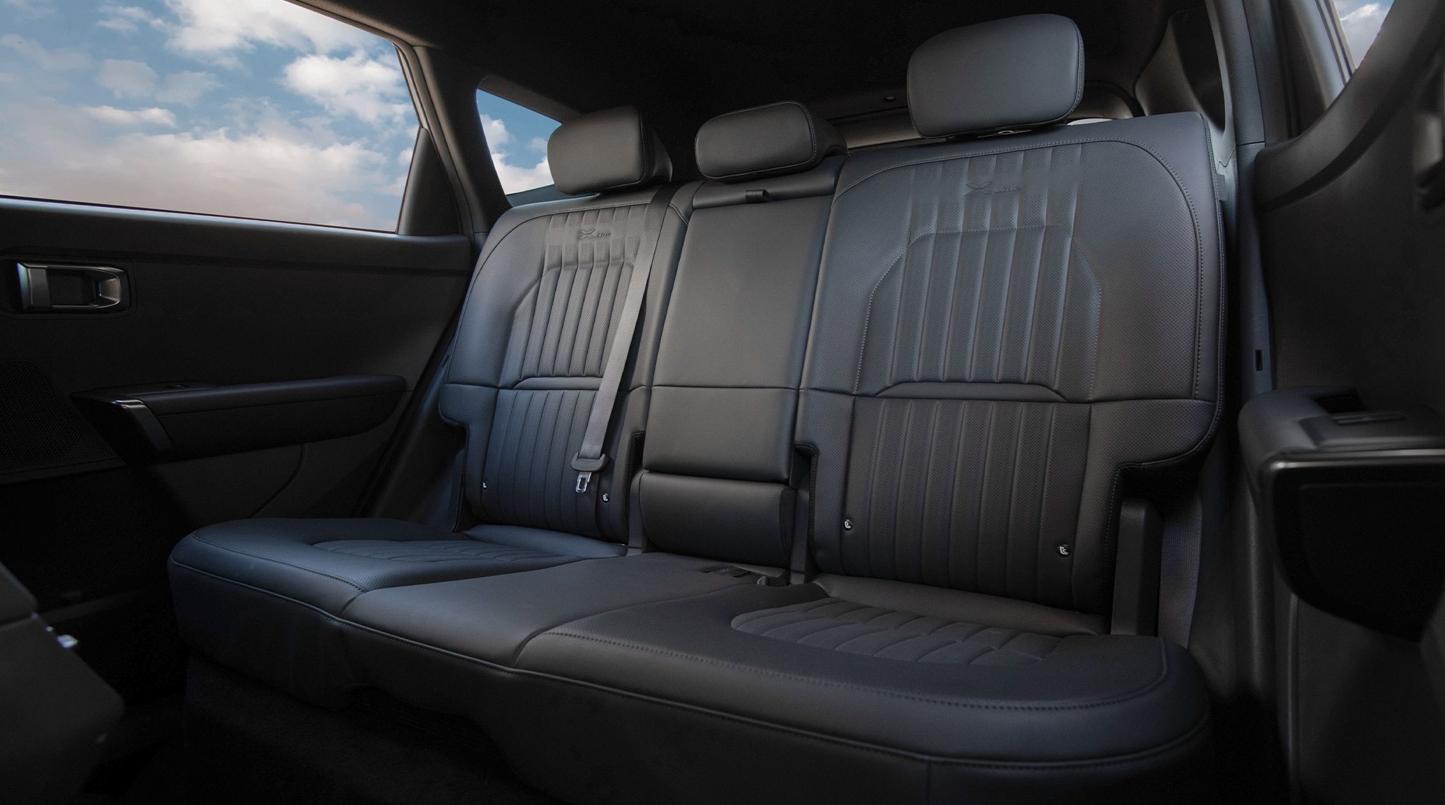 Interior view of the 2027 Kia Seltos Hybrid SUV showing the roomy back row seating space in black, with headrests and comfortable seating for three.