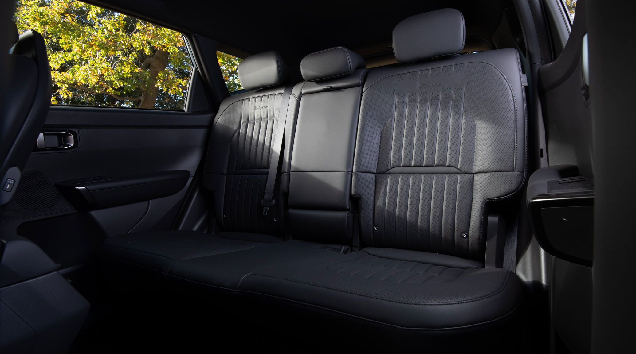 Interior view of the 2027 Kia Seltos SUV showing the roomy back row seating space in black, with headrests and comfortable seating for three.