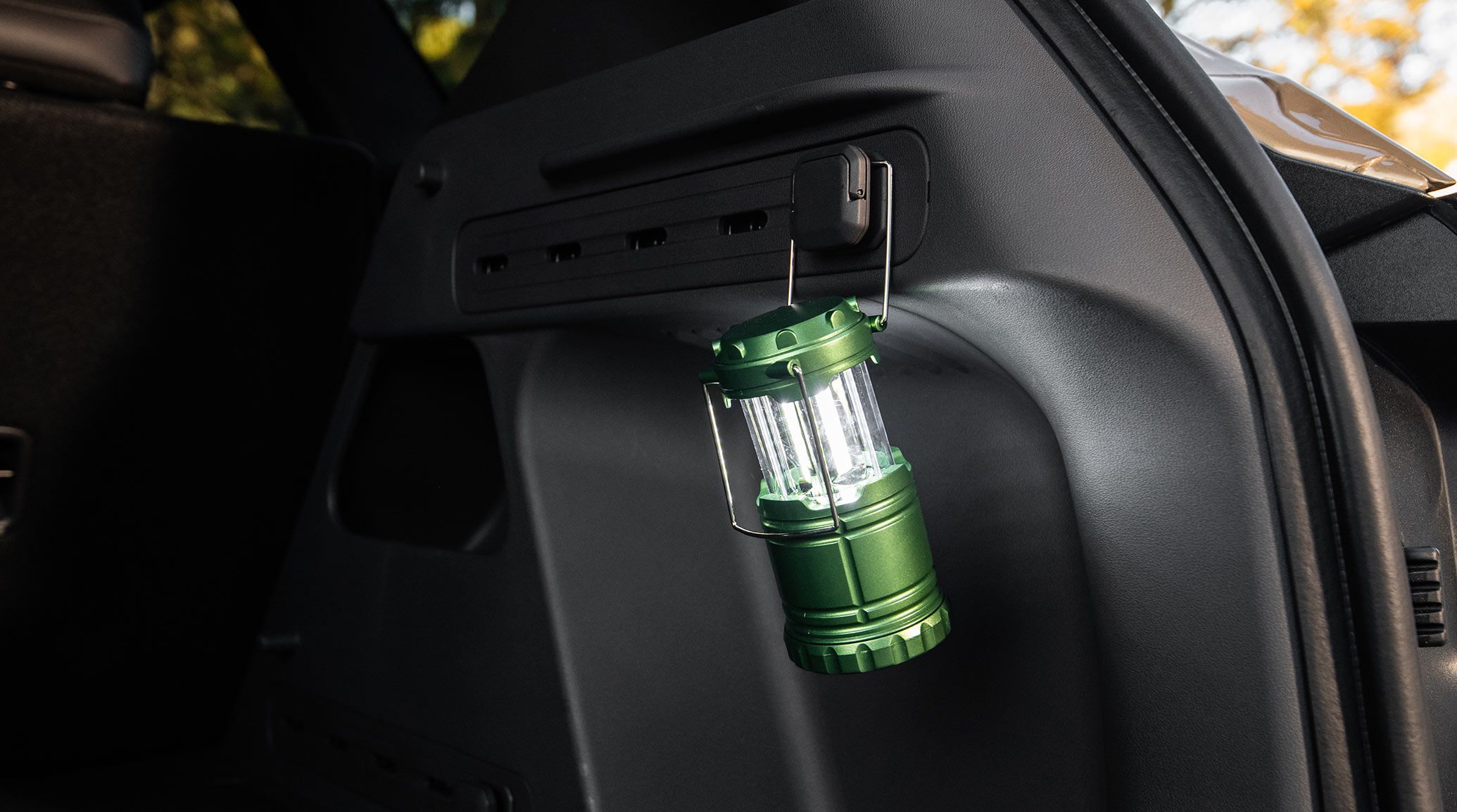 Cargo management area of the 2027 Kia Seltos with a green lantern hanging from an interior hook, showing the vehicle’s cargo system that helps you organize your belongings.