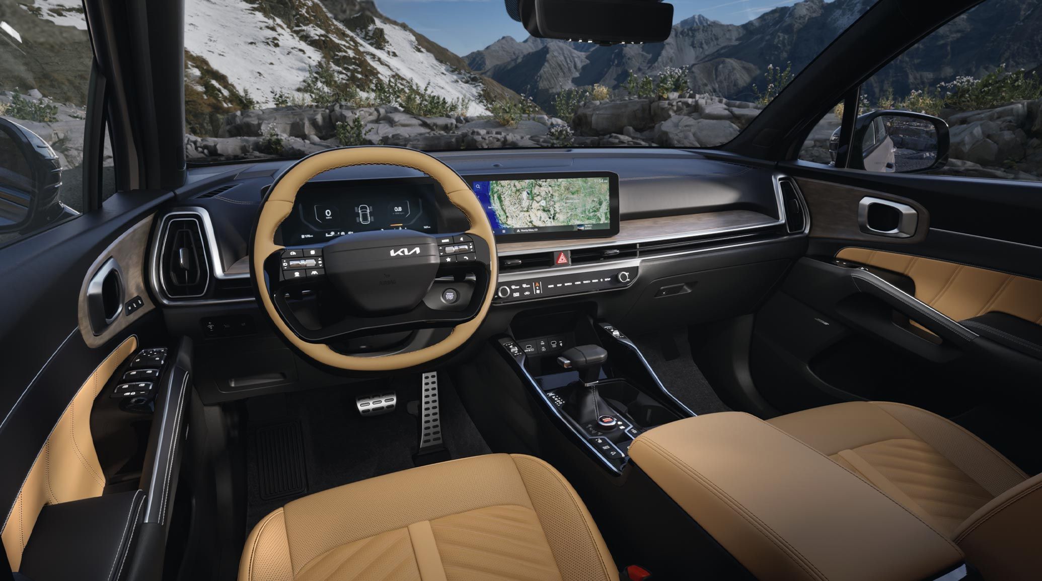 Interior angled photo of the 2027 Kia Sorento in black and tan, showcasing its steering wheel, dual panoramic display with maps showing, center console, shifter, glove compartment, and more. A snow-filled forest is visible through the windshield.