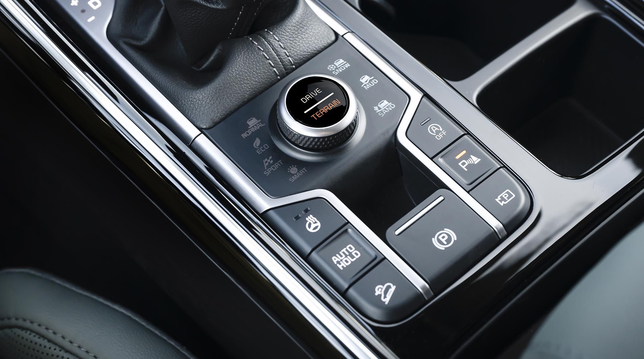Close-up interior view of the 2027 Kia Sorento SUV driver's center console highlighting the gear shifter showing buttons with snow mode, parking assist, heated steering wheel, eco mode, and more.