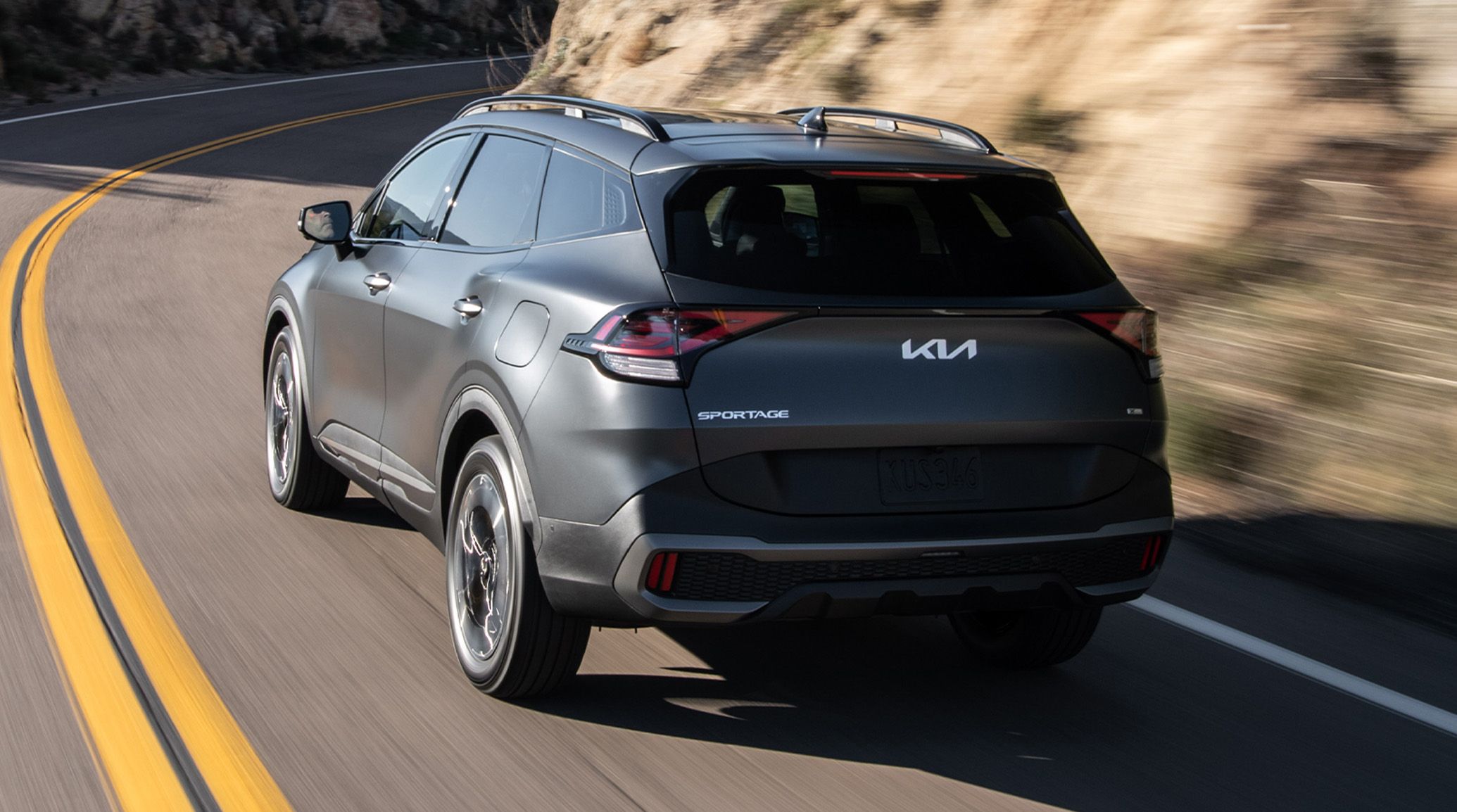 2024 Kia Sportage PHEV driving around curve on highway.