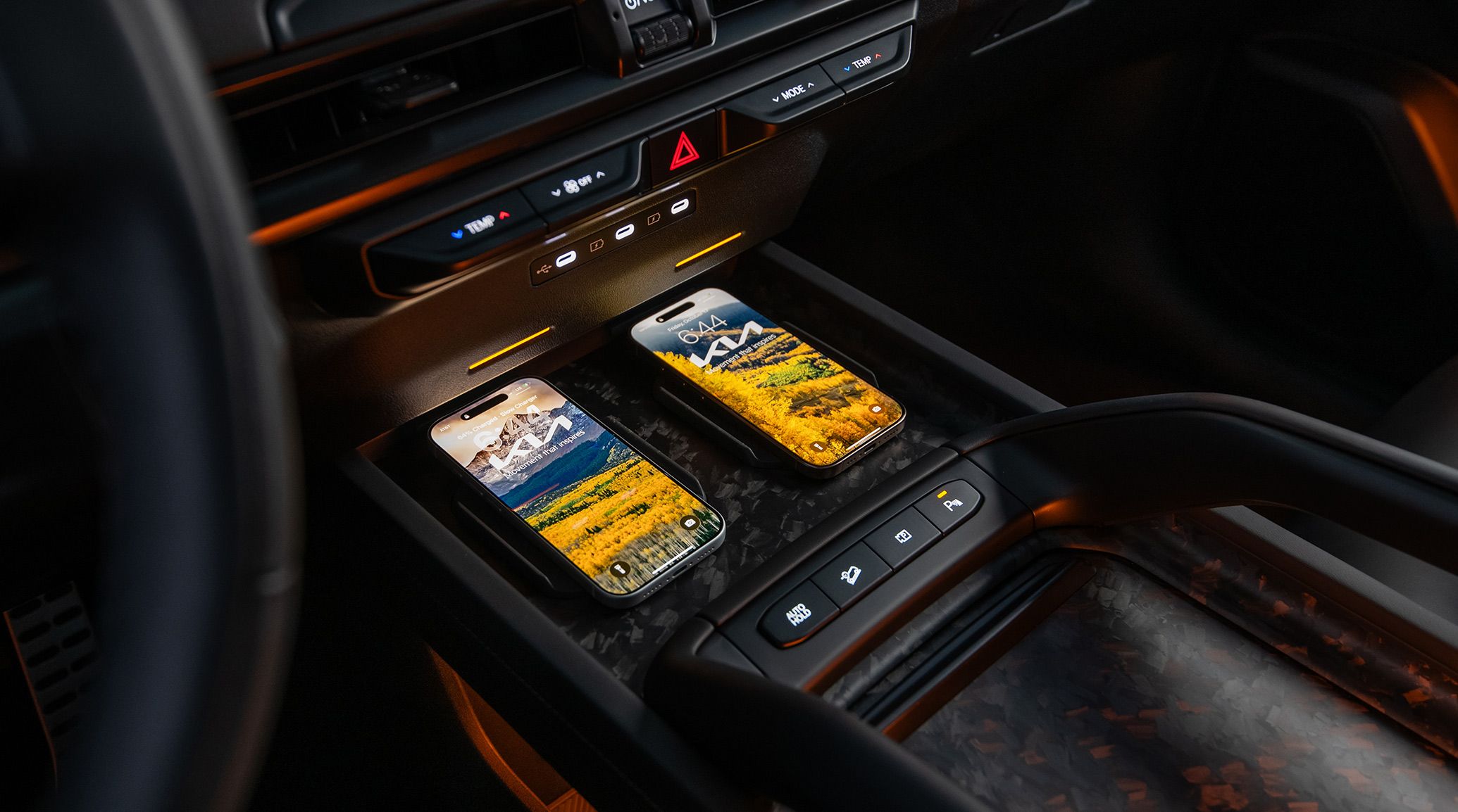 Close-up interior view of the 2027 Kia Telluride wireless charging station holding two fully charged smartphones, highlighting the modern tech features.