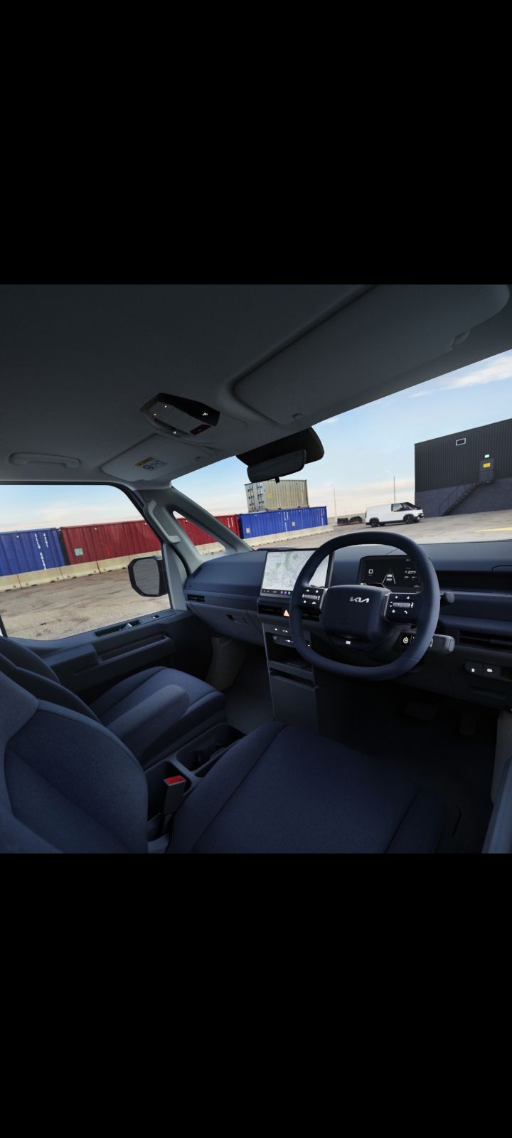 Front driver’s view of Kia PV5 interior showing steering wheel and infotainment display