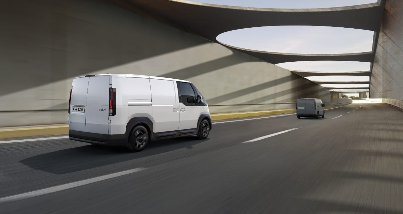 Rear view of the Kia PV5 Cargo driving on highway with another van ahead