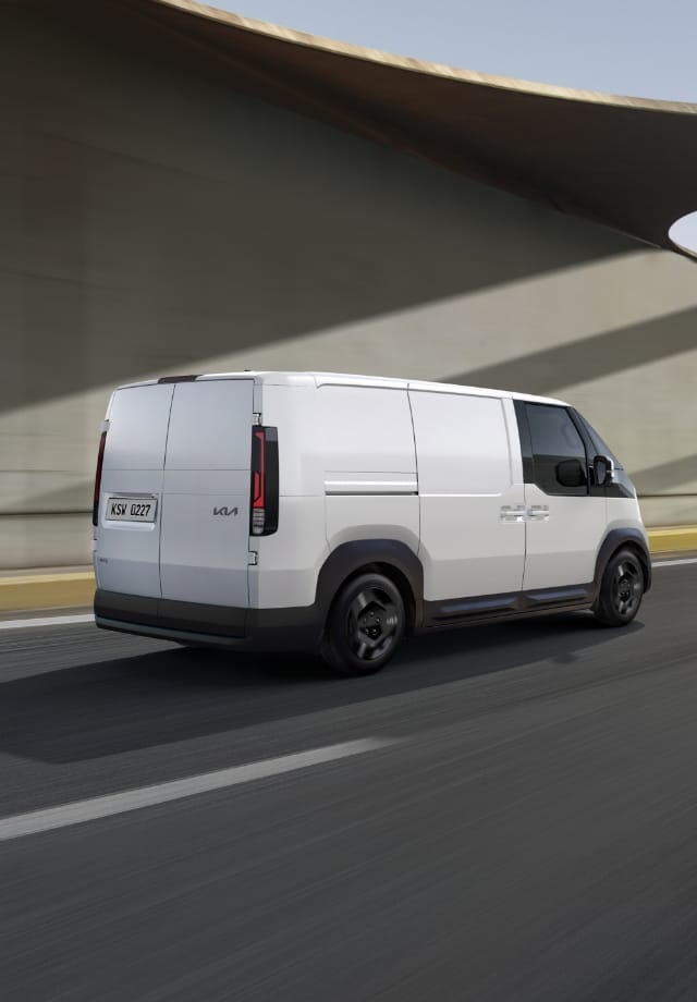 Rear view of the Kia PV5 Cargo driving on highway with another van ahead