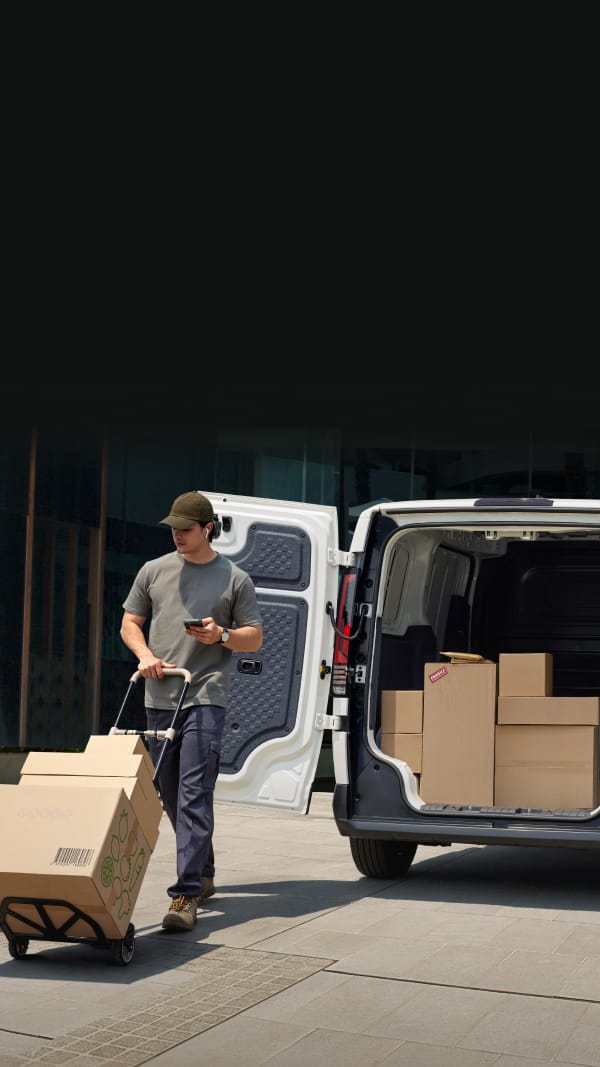 Delivery worker unloading boxes from the Kia PV5 Cargo rear