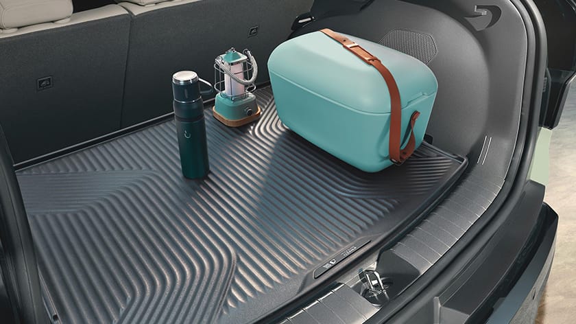 Trunk of a Kia EV3 with a cargo mat, cooler, lantern, and thermos