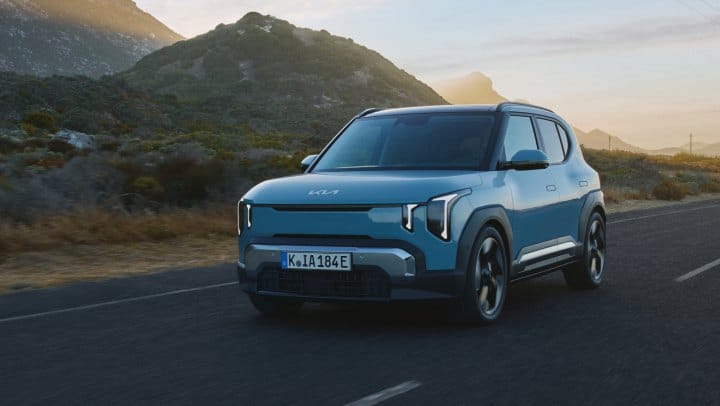Blue Kia vehicle driving on a mountain road