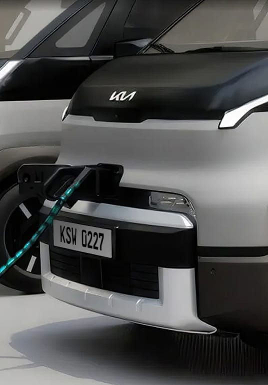 Partial front view of the Kia PV5 Cargo connected to charging station