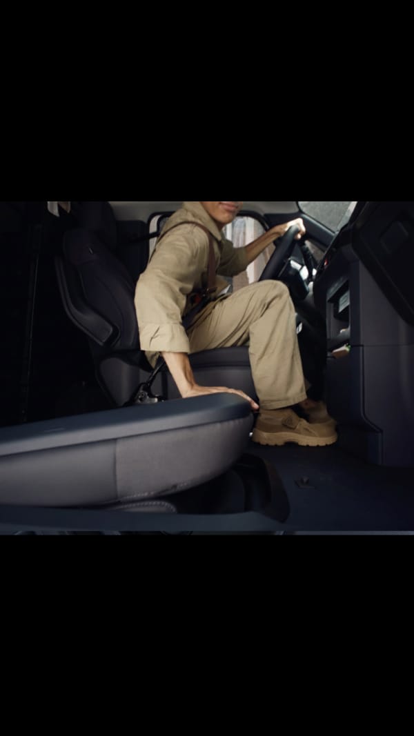 Conductor sujetando el volante del Kia PV5 Cargo con la pantalla de navegación visible