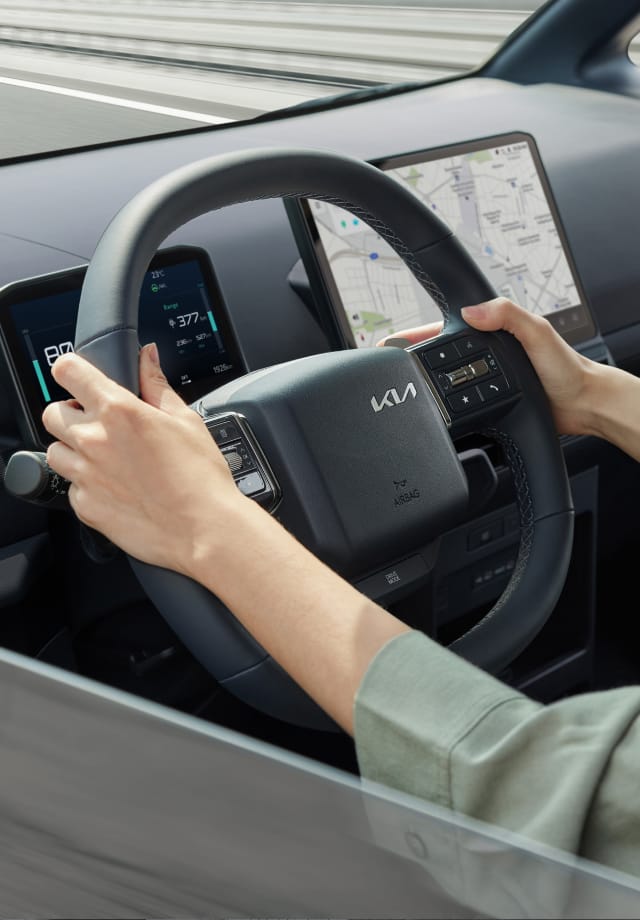 Primer plano de un conductor sujetando el volante del Kia PV5