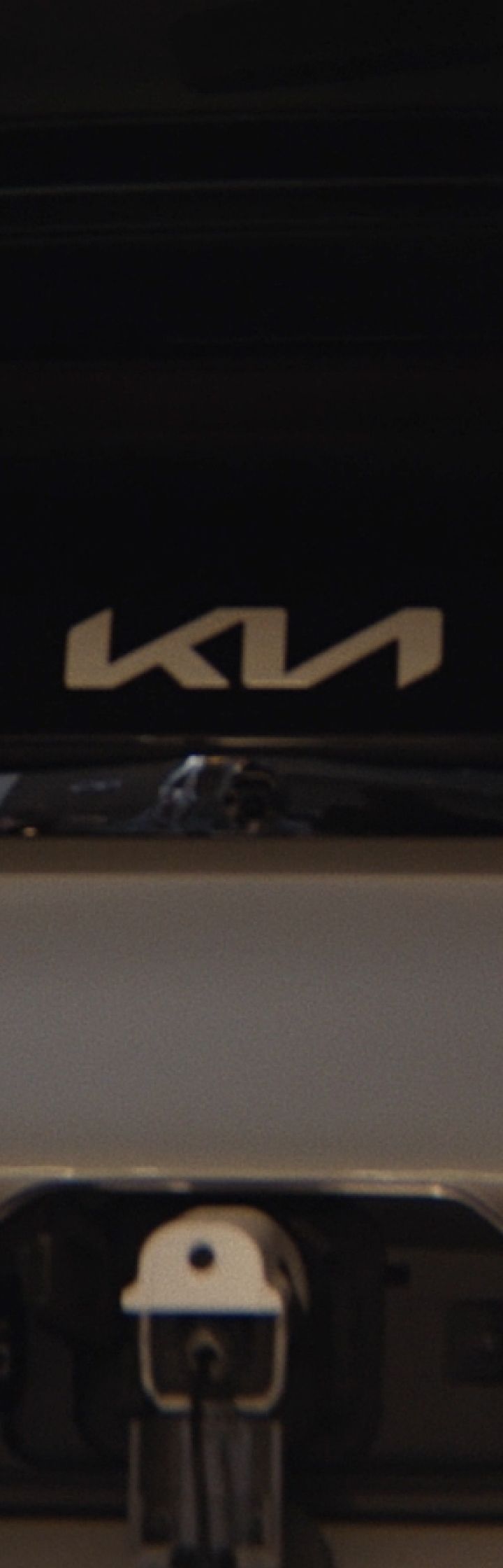Vista trasera del Kia PV5 Cargo cargándose con un hombre trabajando en un ordenador portátil cercano