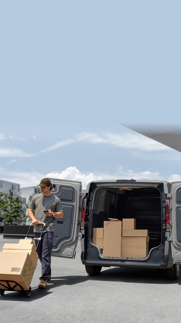Trabajador de reparto descargando cajas desde la parte trasera del Kia PV5 Cargo