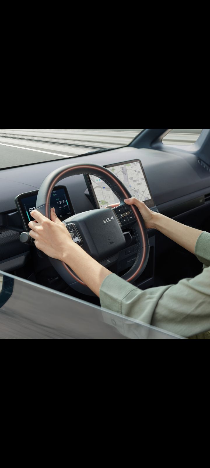 Close-up of the Kia PV5 Cargo steering wheel with driver’s hands