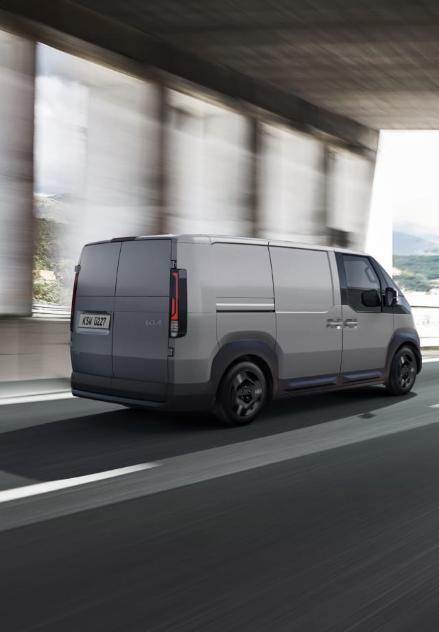 Rear view of the Kia PV5 Cargo driving on highway with another van ahead