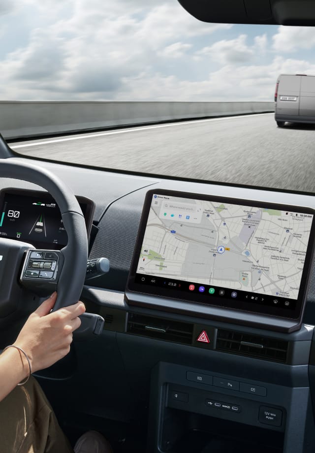 Interior view from driver’s seat with hands on wheel and navigation screen visible