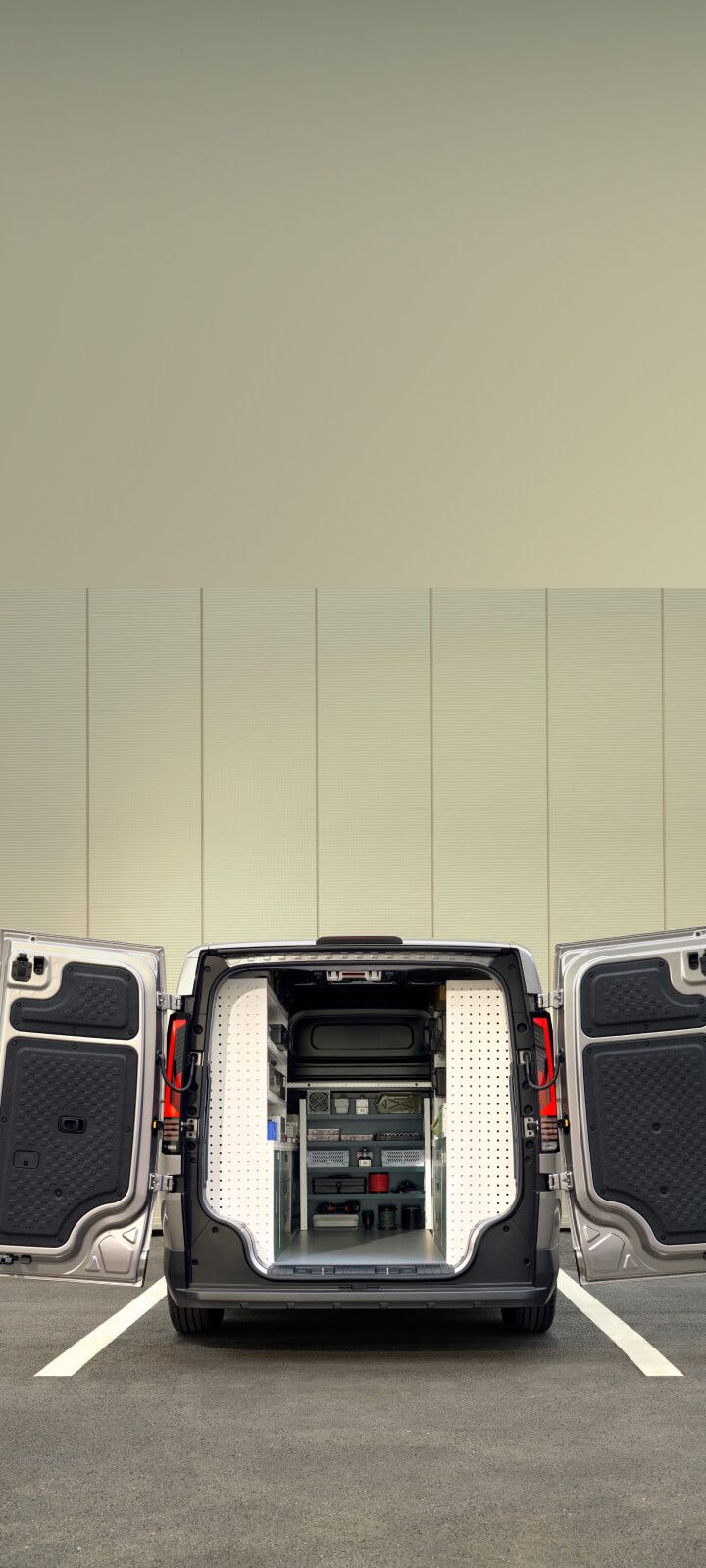 Female worker carrying toolbox beside the Kia PV5 Cargo with rear storage open