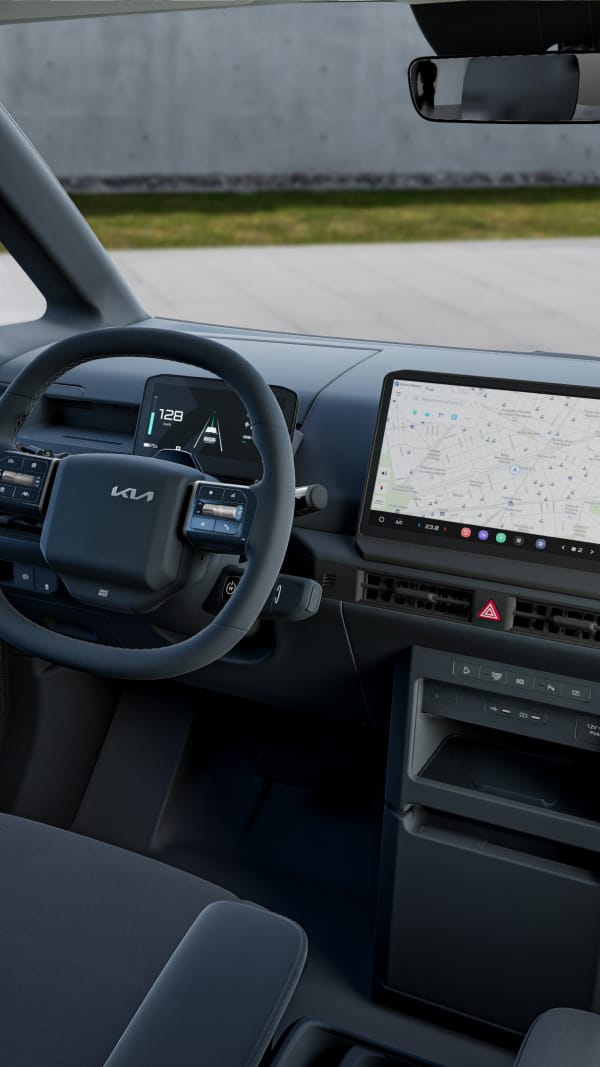 Wide view of the Kia PV5 Passenger cockpit featuring a 7.5-inch digital cluster, heated steering wheel, climate-controlled seats, and a large navigation display for enhanced comfort and control