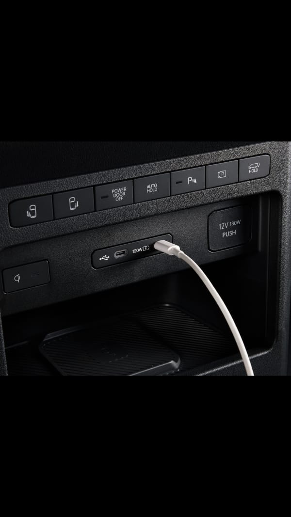 Close-up of the Kia PV5 Passenger dashboard USB port with cable connected