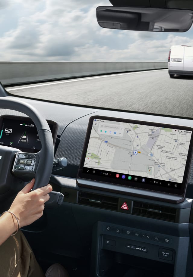 Interior view from the driver's seat with hands on the wheel and the navigation screen visible