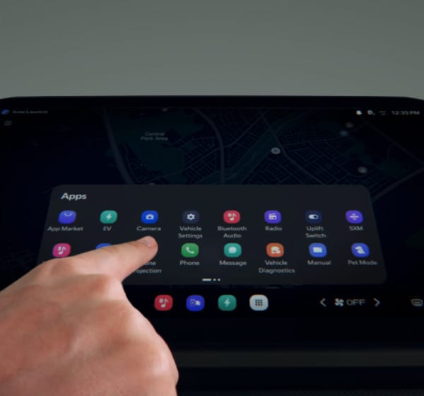 A finger selecting an app on an infotainment touchscreen