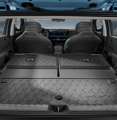 Rear cargo view of a Kia SUV interior showing a textured rubber cargo liner covering the trunk floor, with rear seats and dashboard visible through the open tailgate.
