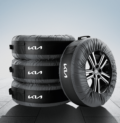 Three Kia-branded tyre storage bags stacked beside a fourth wheel with tyre encased in a matching protective bag.