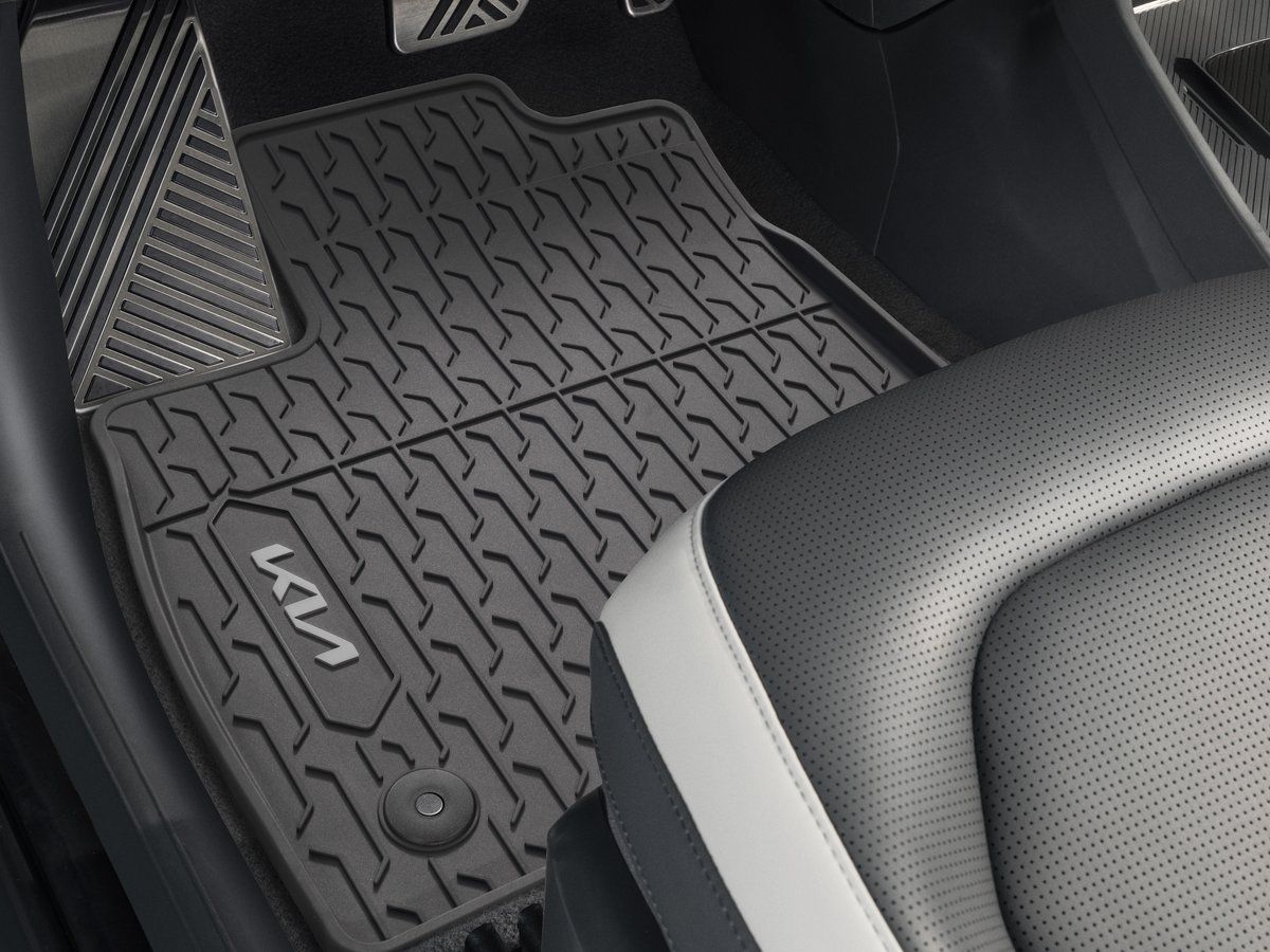 Alfombrilla negra para todo tipo de clima, con el logotipo de Kia, colocada en el espacio para los pies de un Kia EV3.