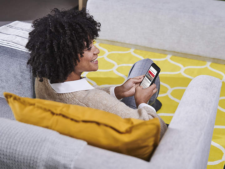 Una mujer sentada en el sofá usando una app de servicios Kia